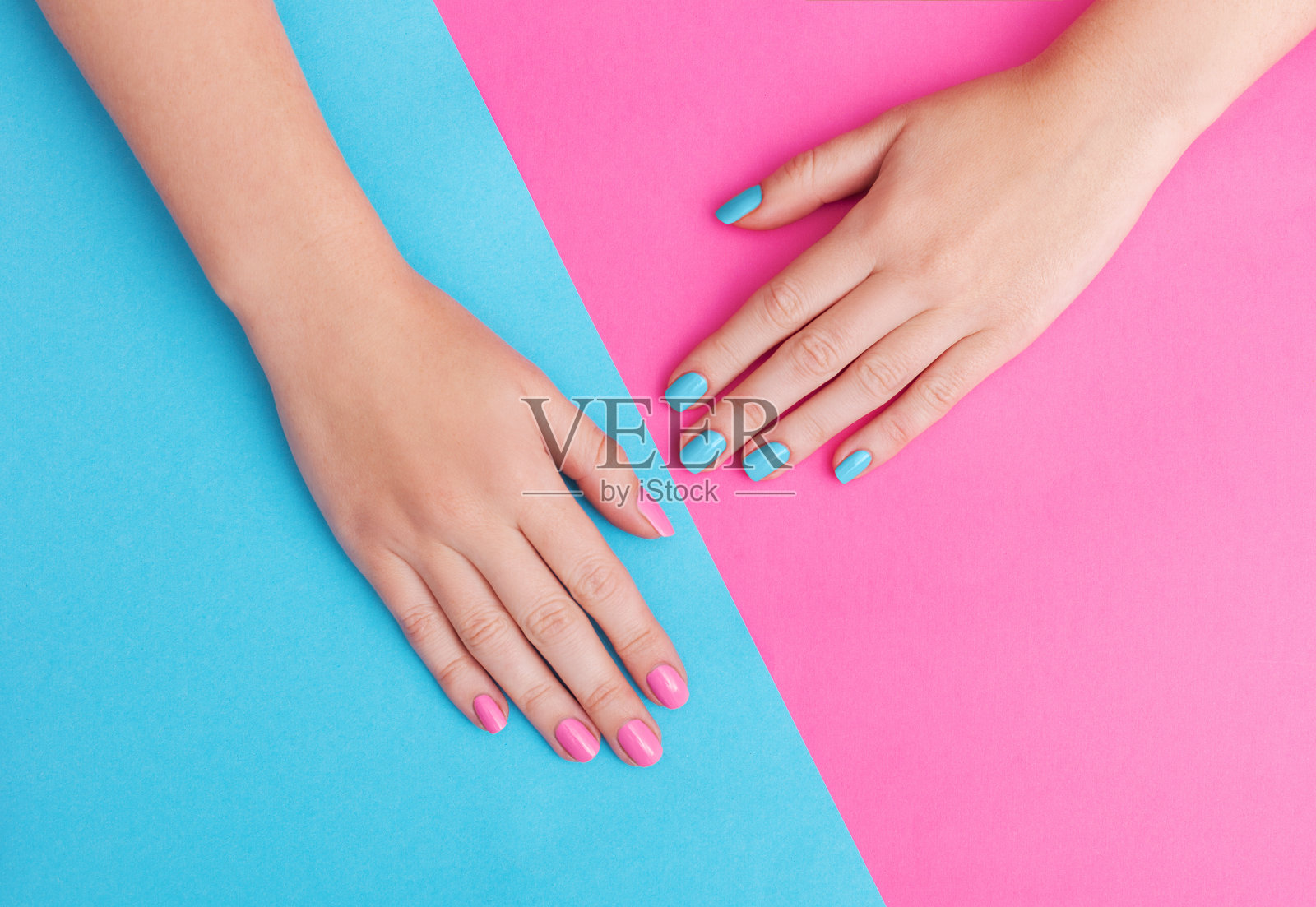 一个年轻女子的手的特写与指甲上的粉红色背景照片摄影图片