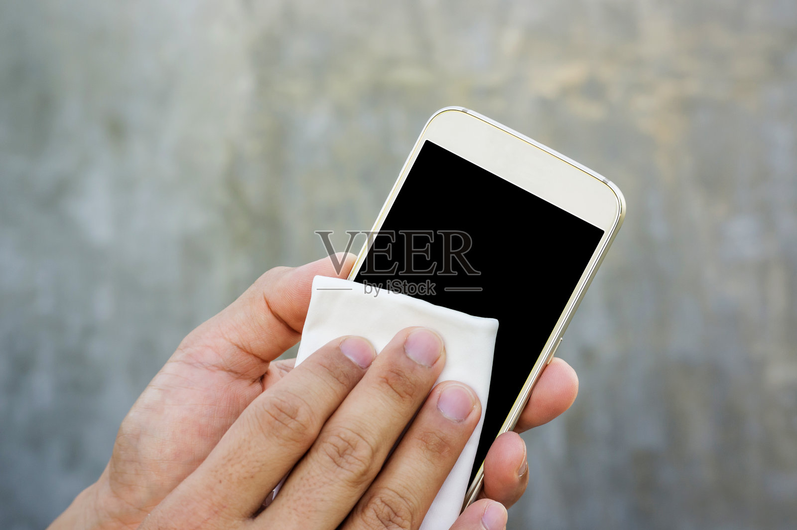 一名男子用超细纤维布擦拭自己的智能手机。照片摄影图片