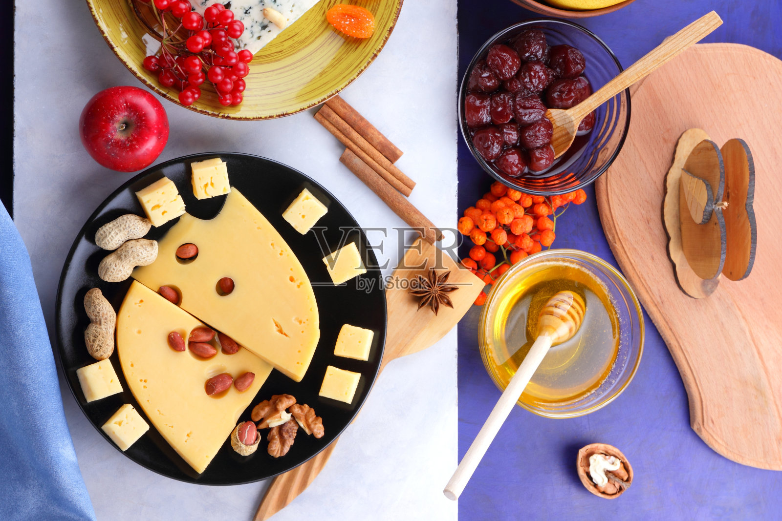 发霉的奶酪、水果、深蓝色背景上有孔的硬奶酪、黑色盘子上的奶酪、水果、坚果、蜂蜜、果酱、圣诞晚餐、五彩缤纷的背景、复古风格照片摄影图片