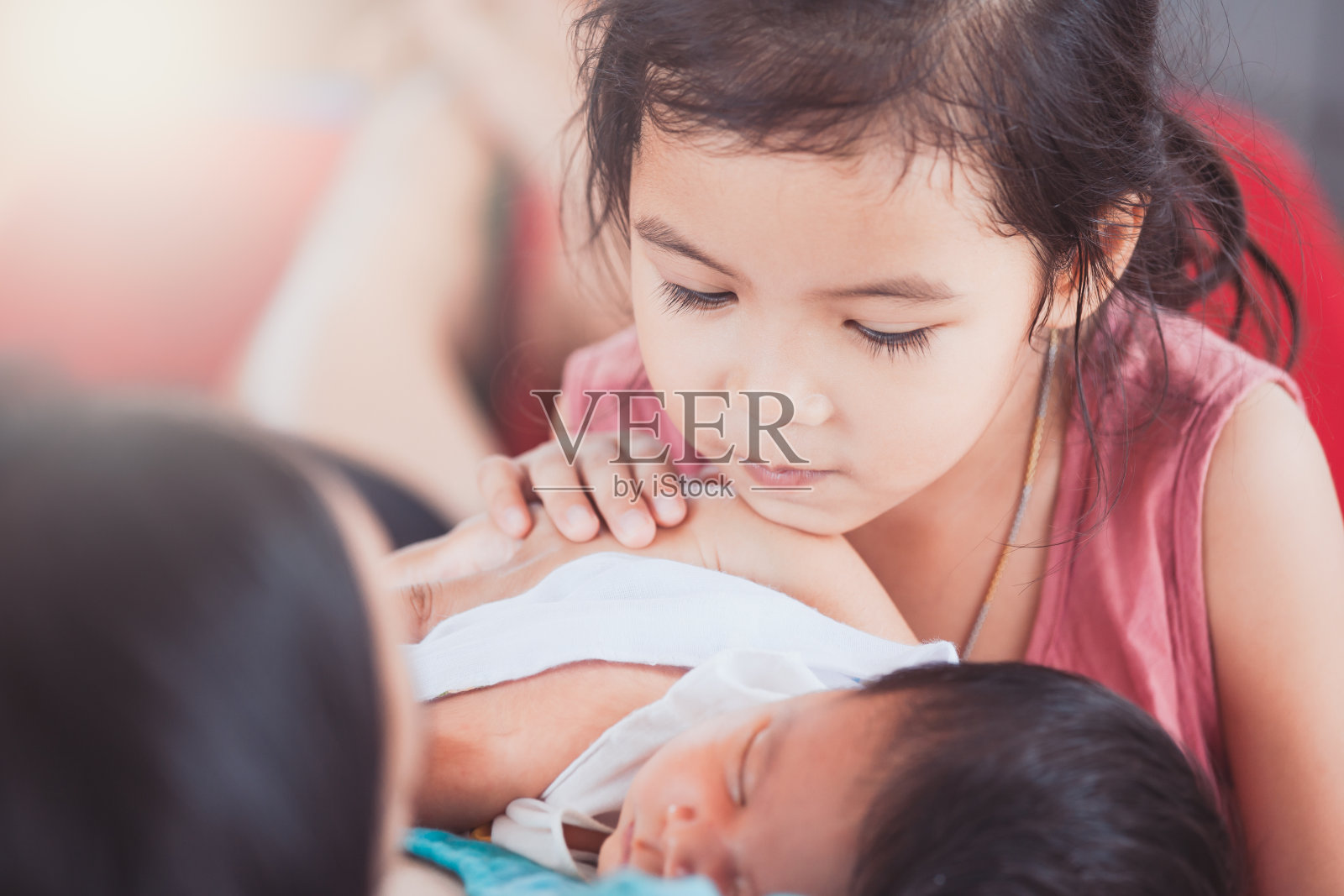 可爱的亚洲小女孩看着她的新出生的妹妹与爱照片摄影图片