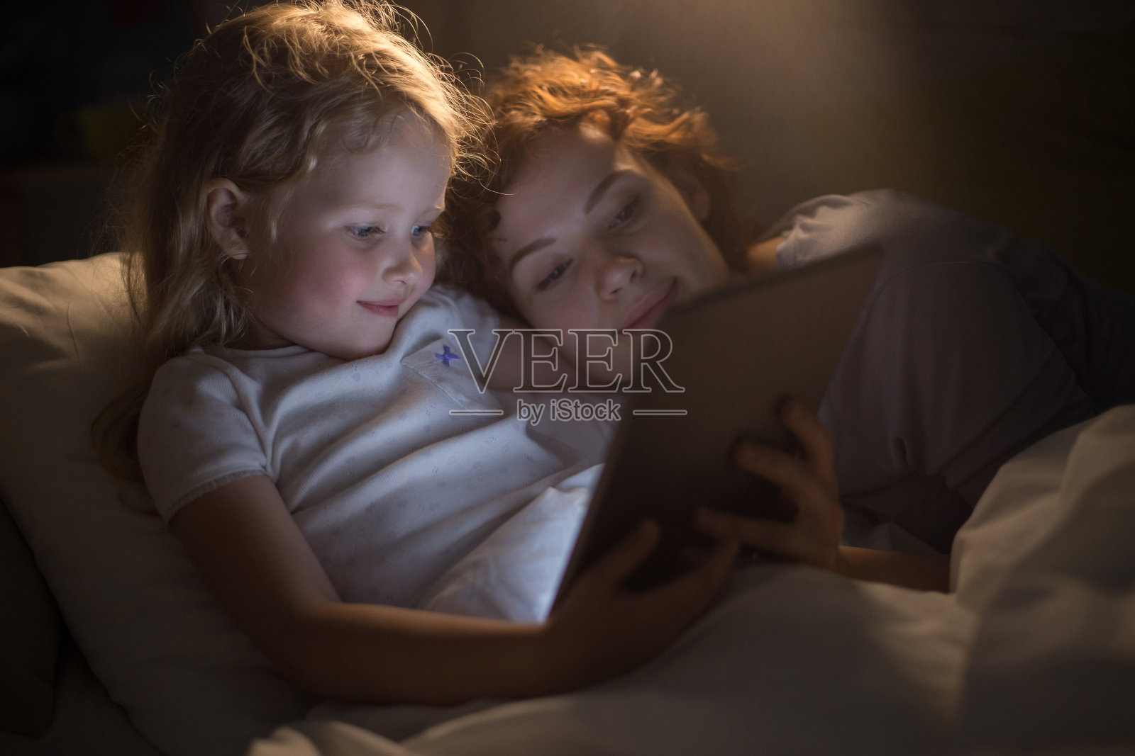 可爱的女孩和妈妈一起看电子书照片摄影图片