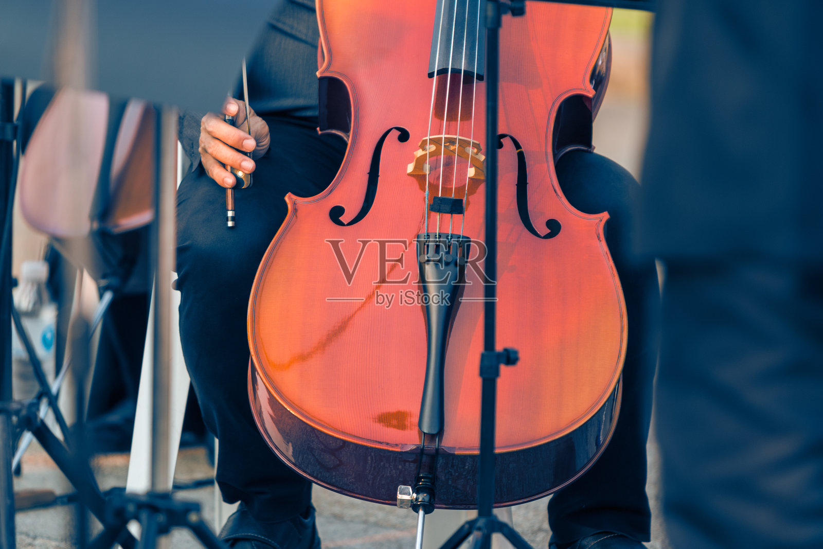 近距离的男性大提琴手拿着大提琴在一个室外音乐会，在温暖的黄金时间晚上的光，有利于音乐或自我兴趣的主题概念照片摄影图片