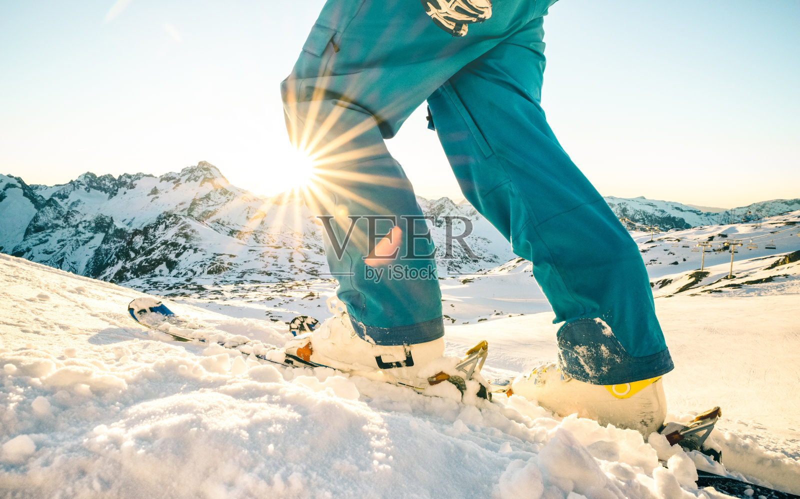 腿的专业滑雪者在日落在法国阿尔卑斯山滑雪胜地放松的时刻-冬季运动概念与冒险的家伙在山顶准备骑下来-侧视图与蓝色的复古滤镜照片摄影图片