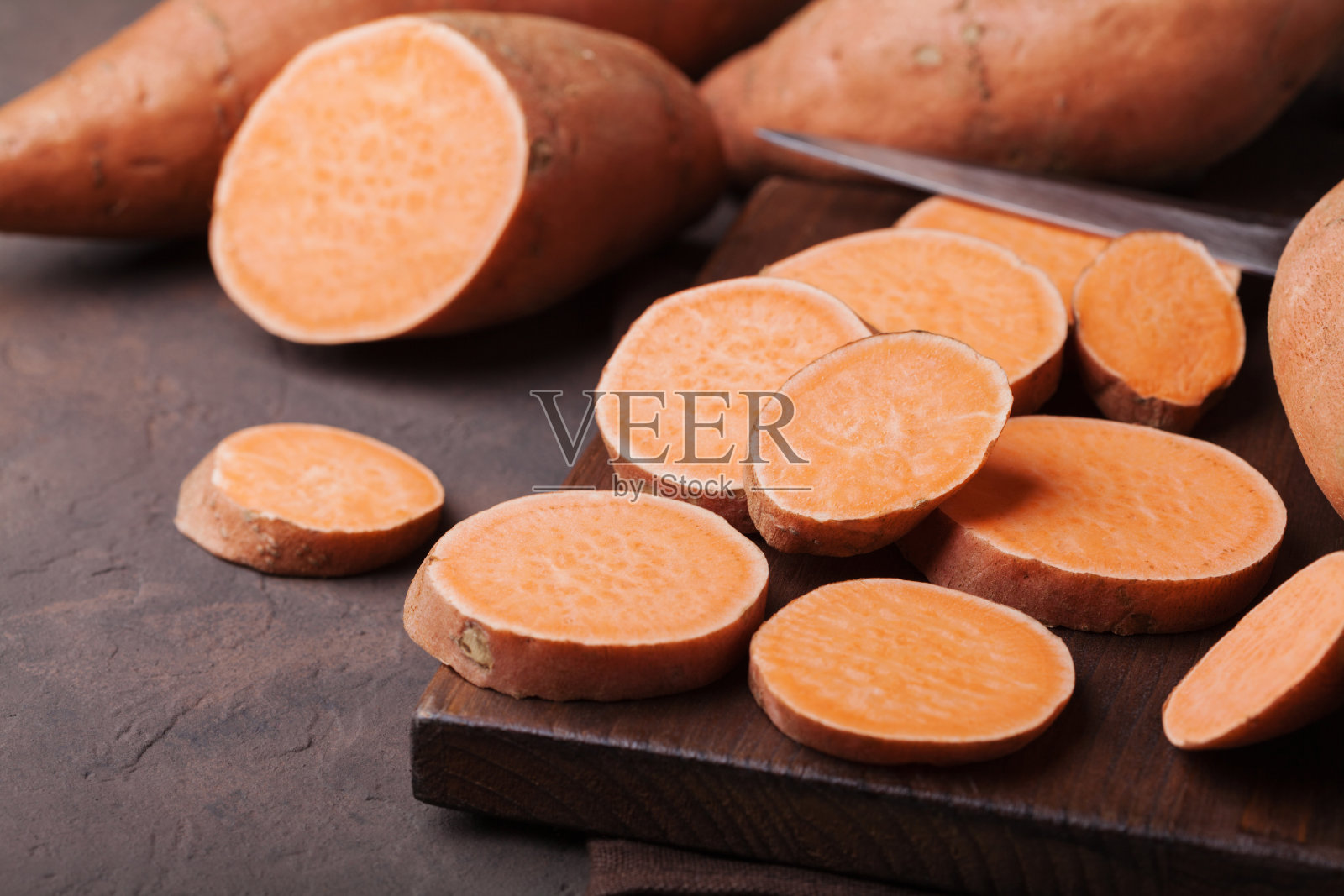 有机生红薯，整块切成薄片，放在厨房木板上。照片摄影图片
