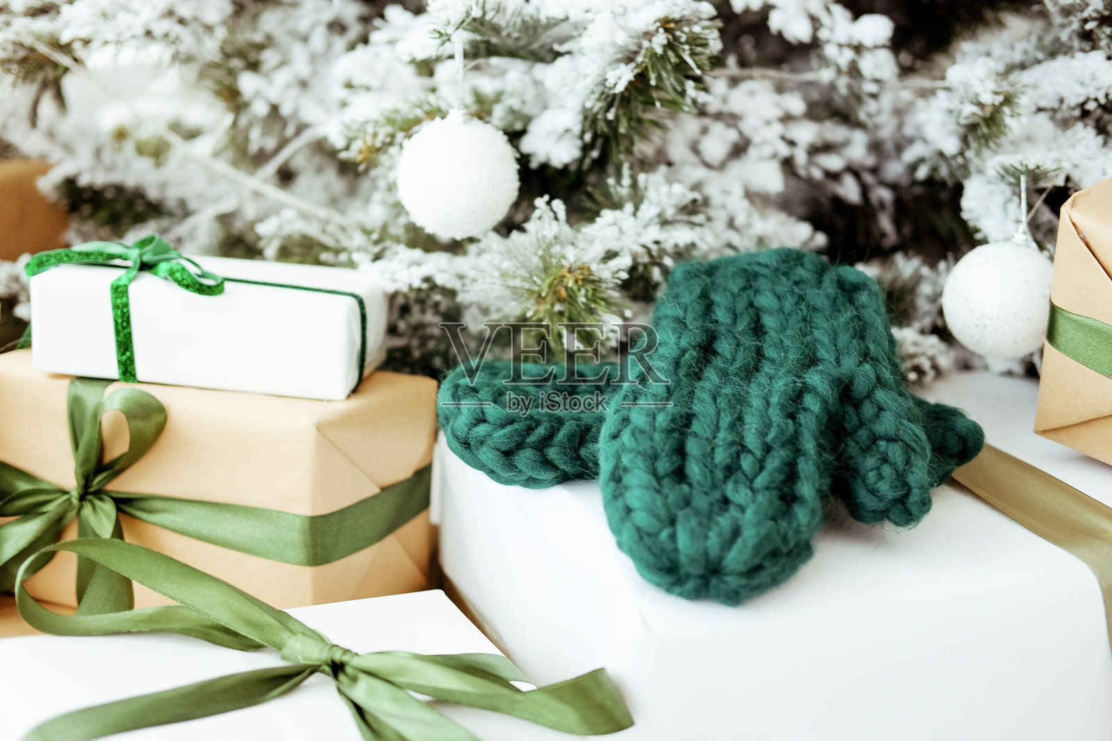 新年树下手工制作的可爱圣诞礼物。编织绿色的手套。照片摄影图片