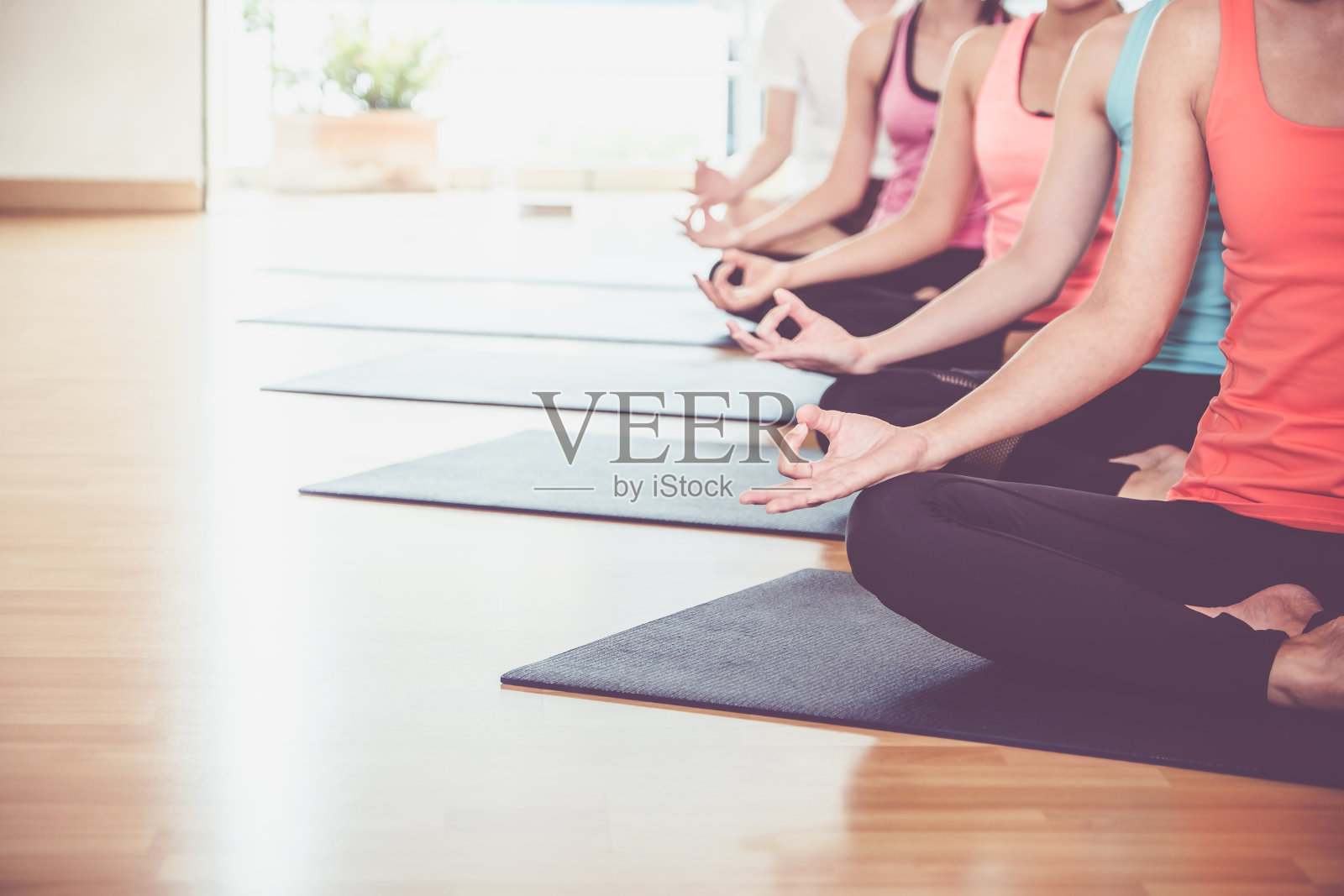 近手瑜伽组坐在做手相和冥想在健身室的训练室，平静和放松的概念，健康和健康的生活方式，留下空间添加文字。照片摄影图片