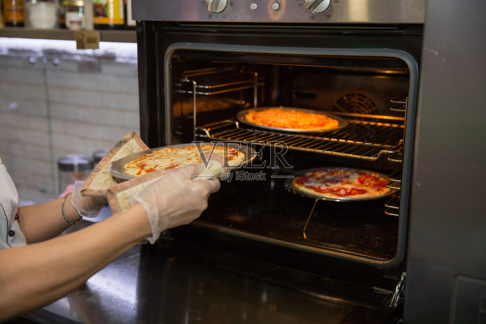 在厨房手套从烤箱拿披萨的厨师的手的裁剪镜头照片摄影图片
