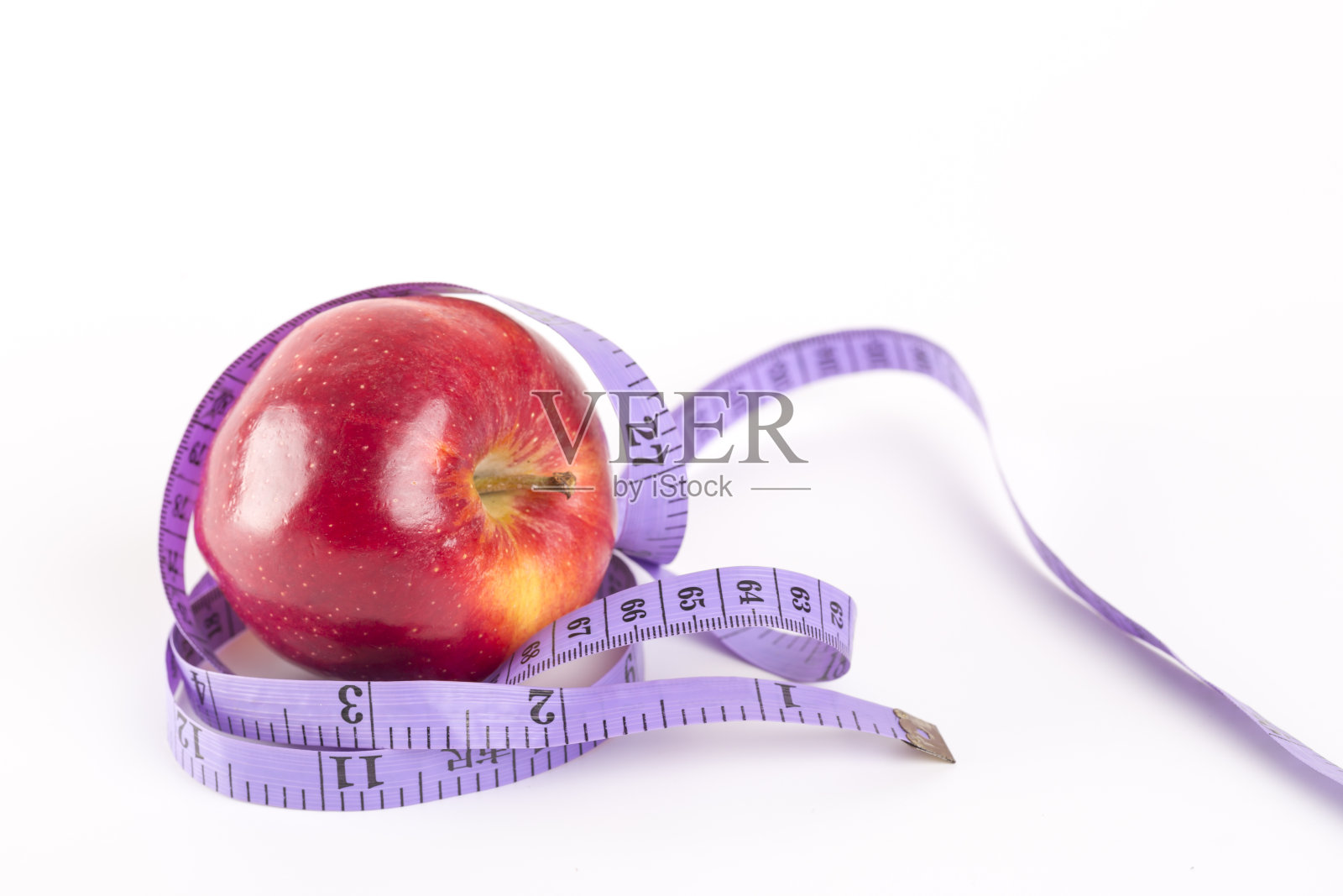 用卷尺绕着一个红苹果。照片摄影图片