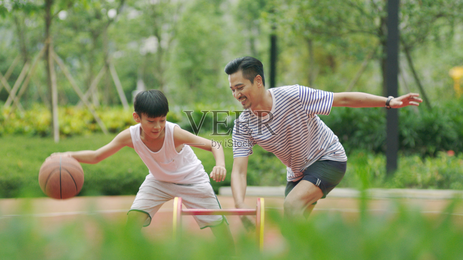 亚洲父亲和儿子在花园里打篮球早上照片摄影图片