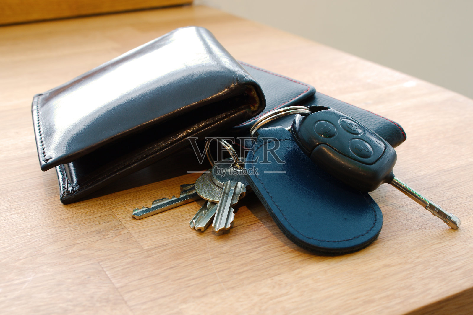 钱包，车钥匙，房间钥匙和手机放在桌子上。照片摄影图片