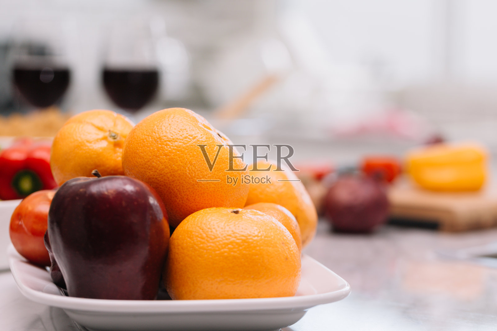 水果一起放在盘子里。由橘子，苹果和红葡萄组成的厨房在家里。照片摄影图片