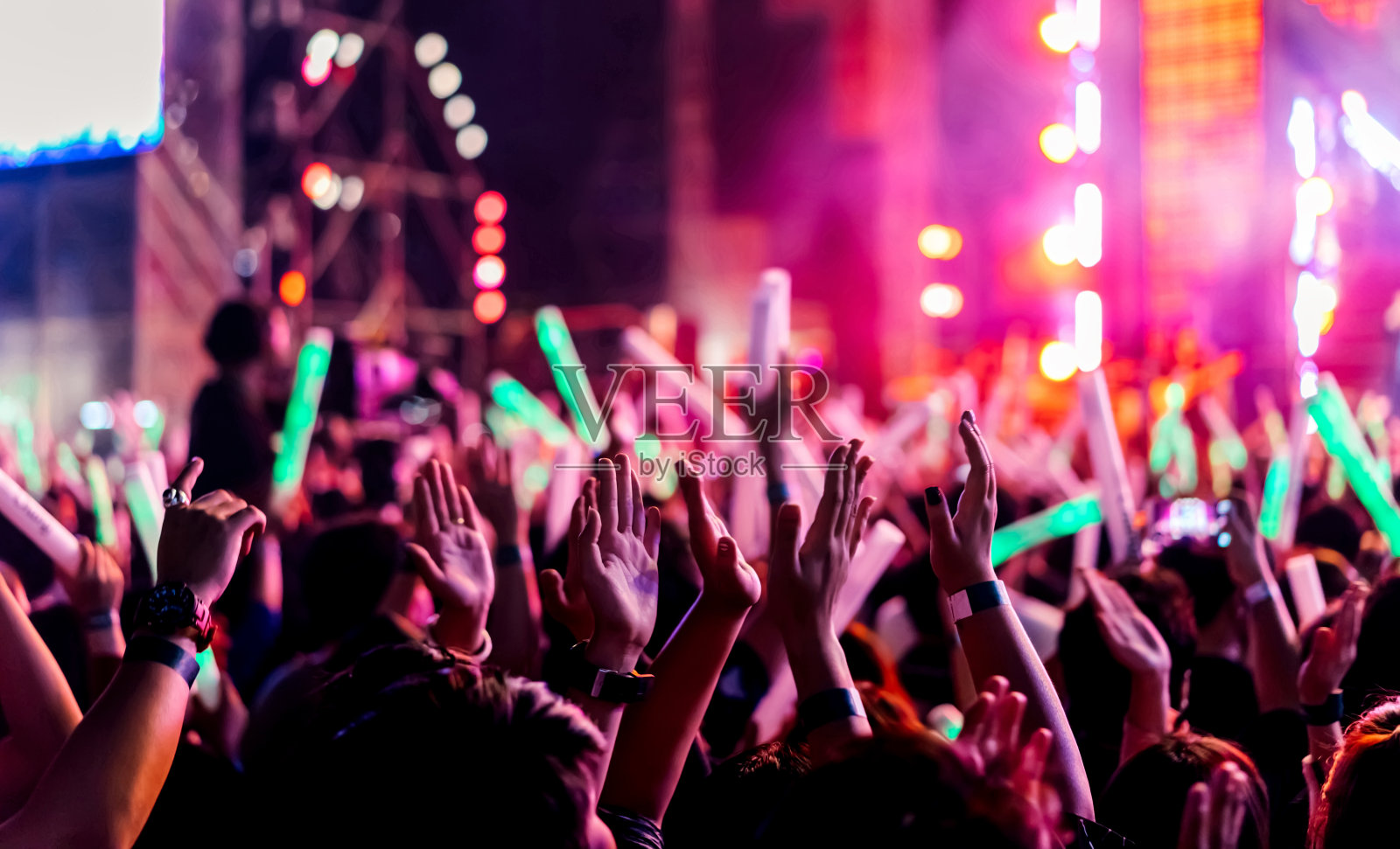 观众在音乐会舞台灯光下鼓掌或举手，歌迷观众举手剪影与聚光灯的辉光效果在音乐节的后视图照片摄影图片