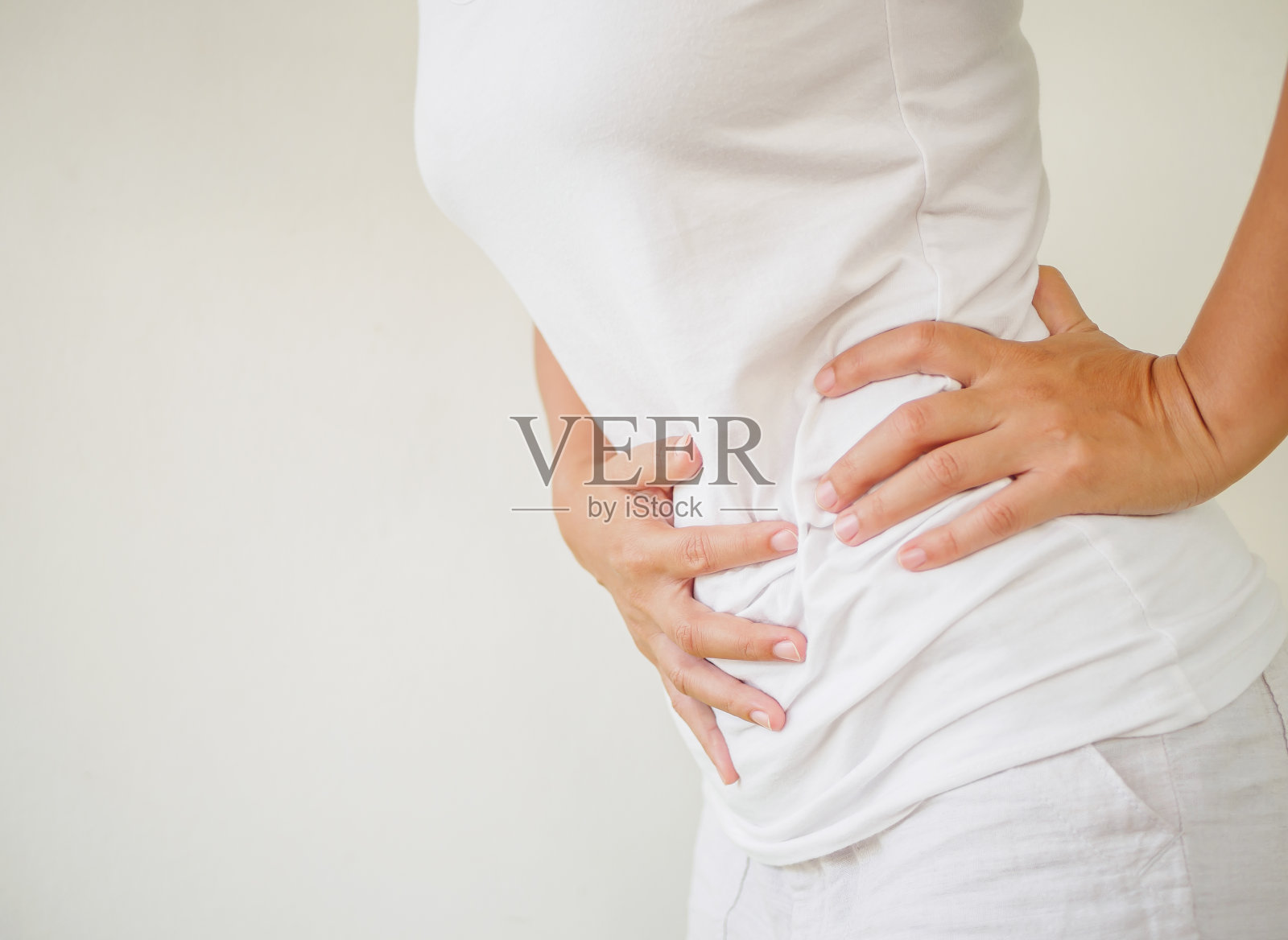 有胃痛或经期疼痛的女性，背景为白色。医疗保健理念。照片摄影图片