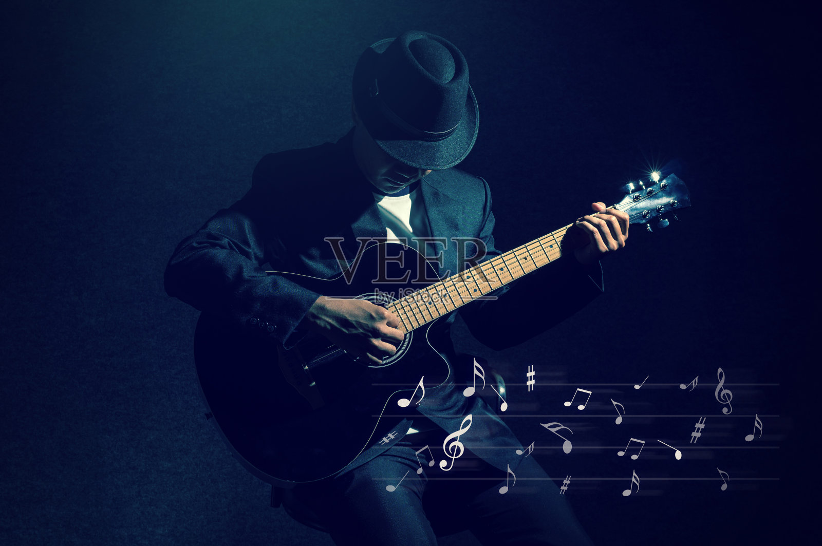 音乐家演奏吉他与音乐音符在黑色的背景，音乐的概念照片摄影图片