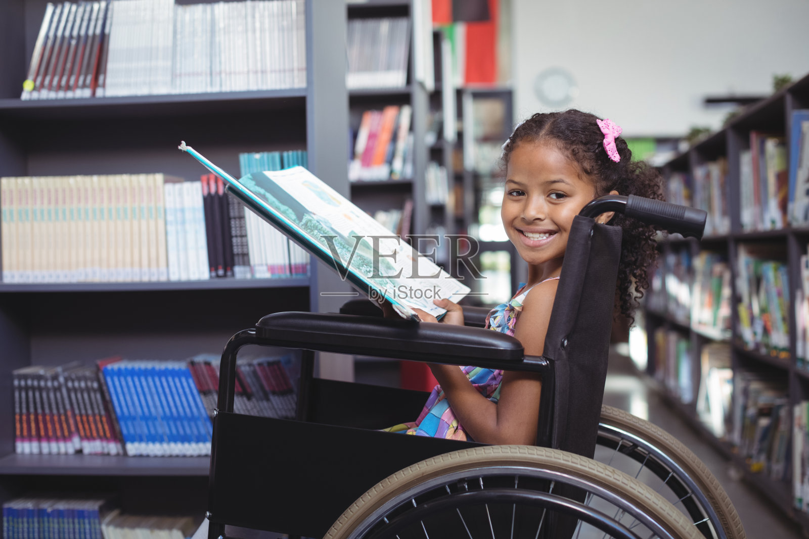 微笑的女孩和书在轮椅上照片摄影图片
