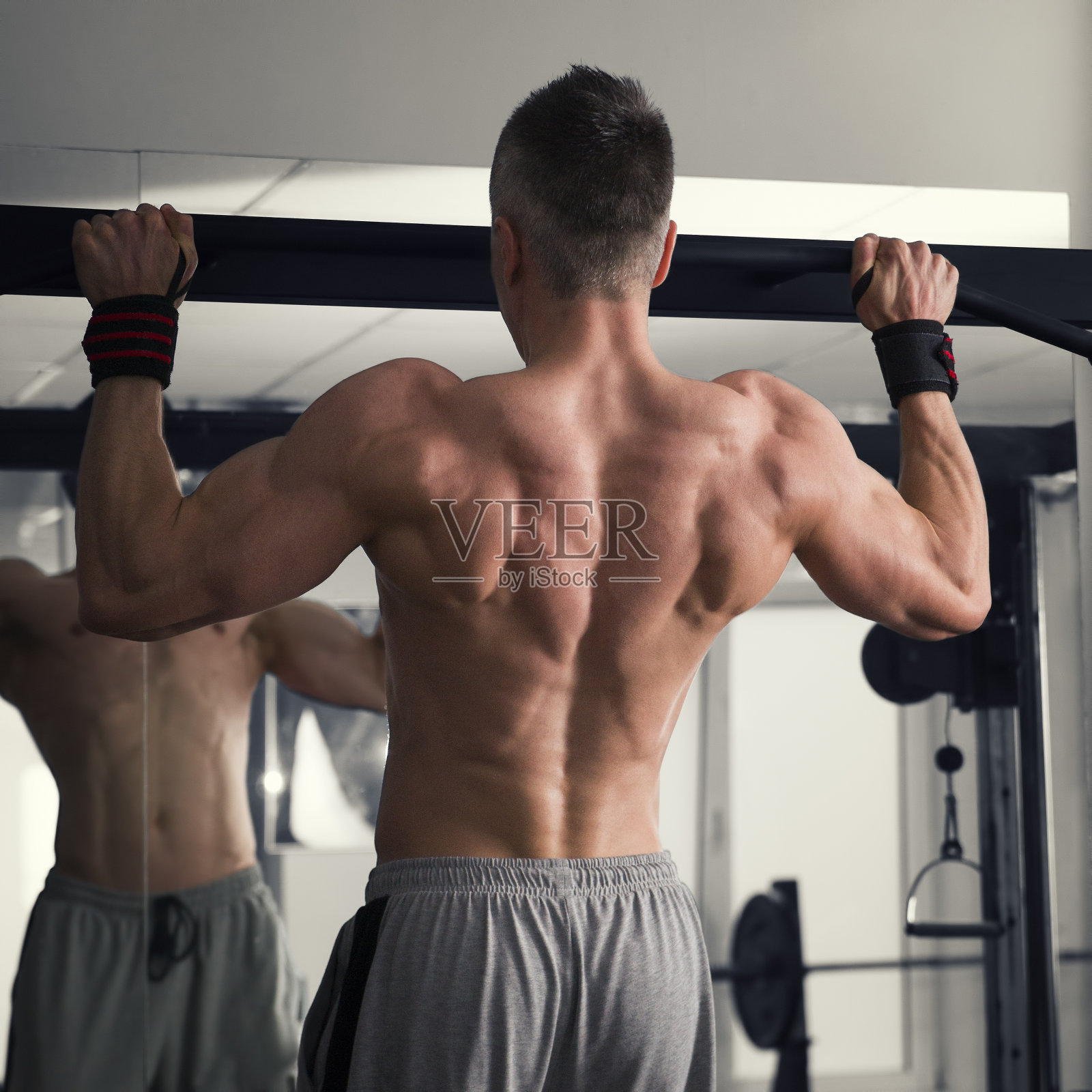 健美运动员在健身房里停下来，肌肉发达的人在单杠上锻炼照片摄影图片