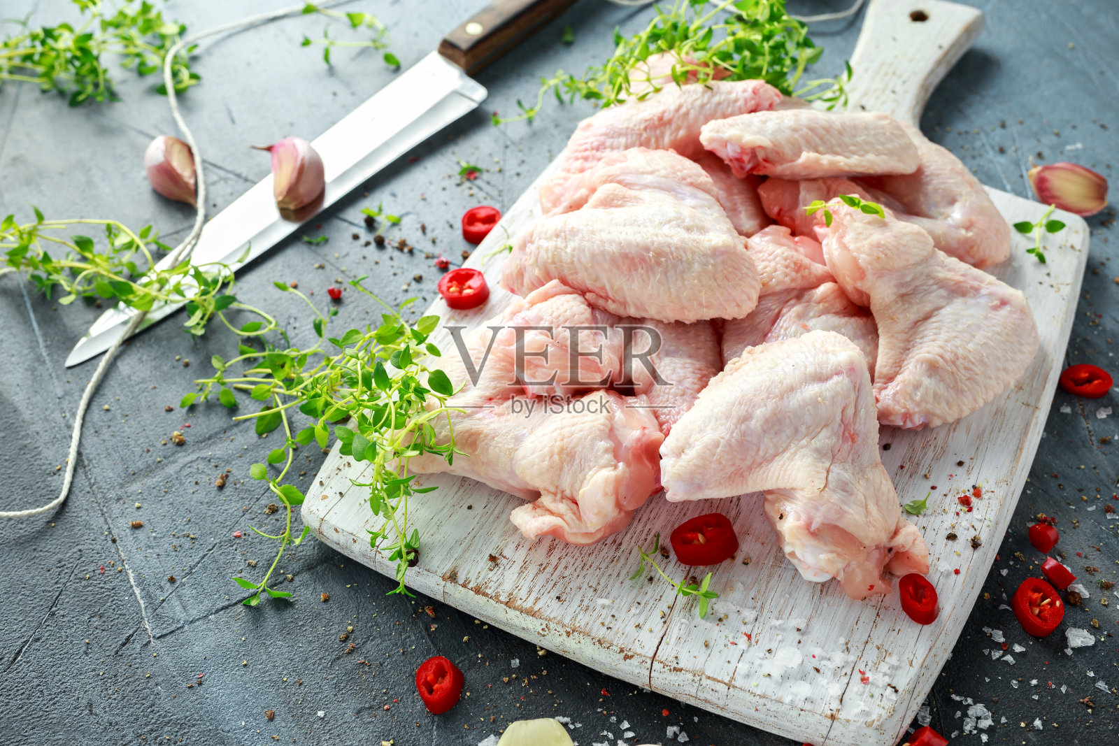 新鲜的生鸡翅放在白色砧板上，加入百里香，辣椒，盐，胡椒，大蒜照片摄影图片