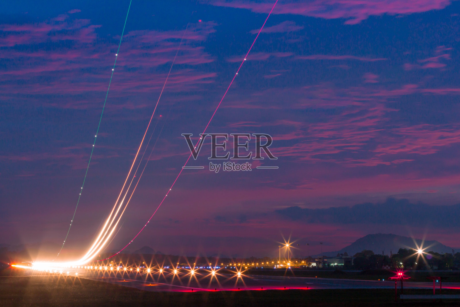 机场跑道上的灯光痕迹，在黄昏的蓝天下。照片摄影图片