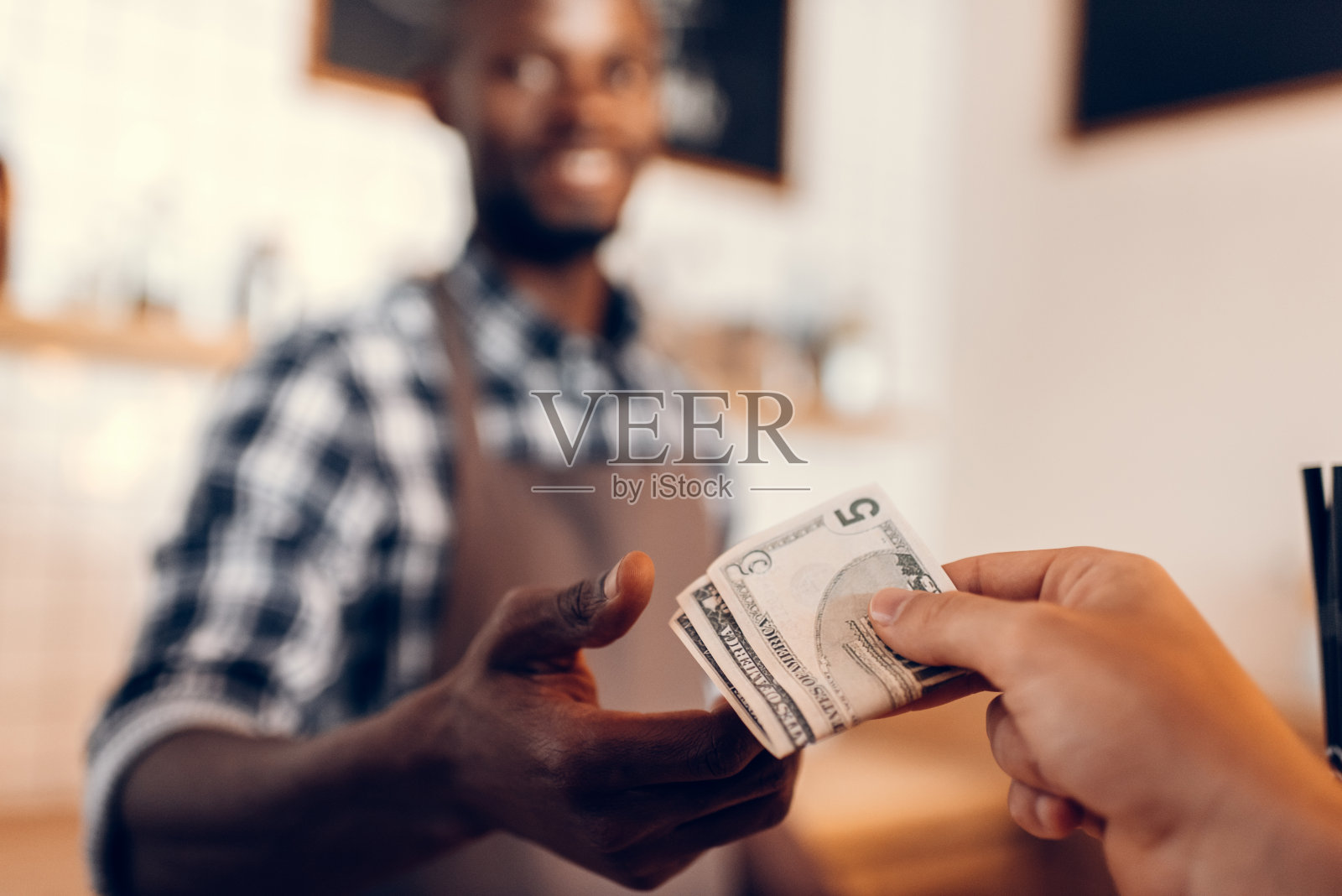 非裔美国咖啡师在咖啡馆柜台接受现金付款的选择性焦点照片摄影图片