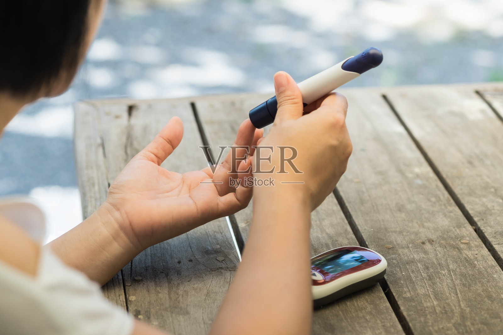 近距离观察妇女双手用刺针在手指上检查血糖水平，血糖仪作为药物，糖尿病，血糖，保健和人的概念。照片摄影图片