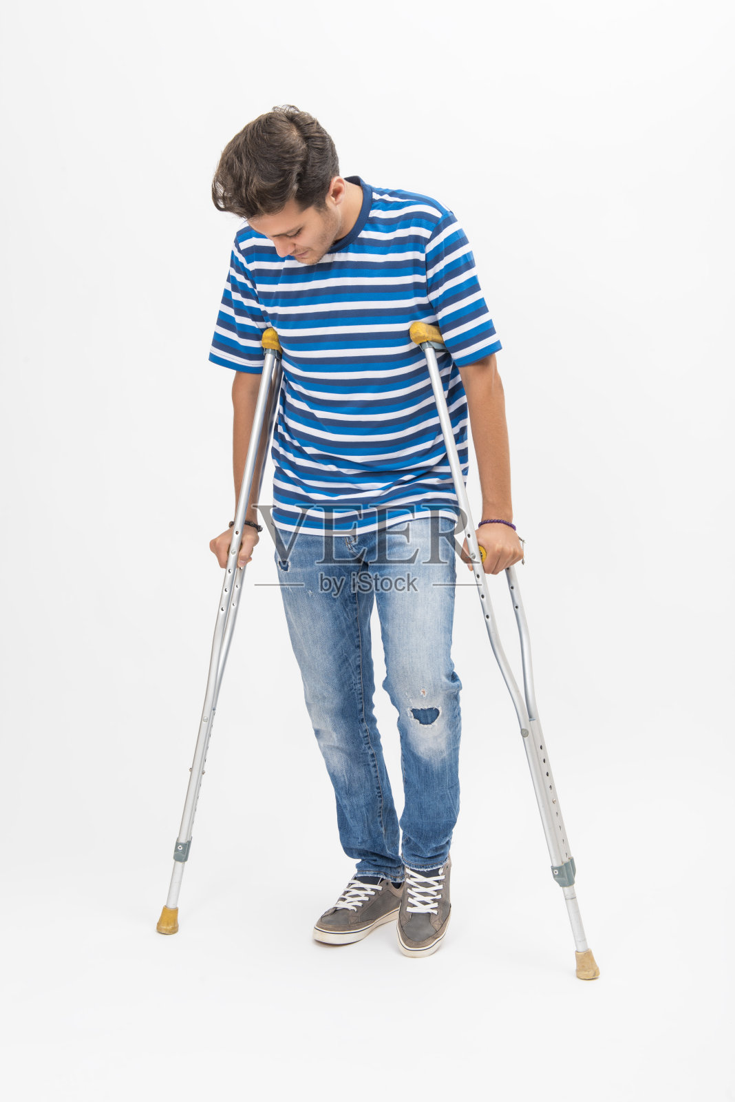 一个拄着拐杖试图在白色背景上行走的残疾青年照片摄影图片