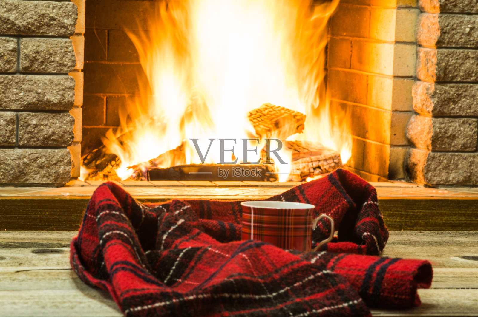 红杯的茶和舒适温暖的围巾靠近壁炉，在乡村别墅，寒假，水平。照片摄影图片
