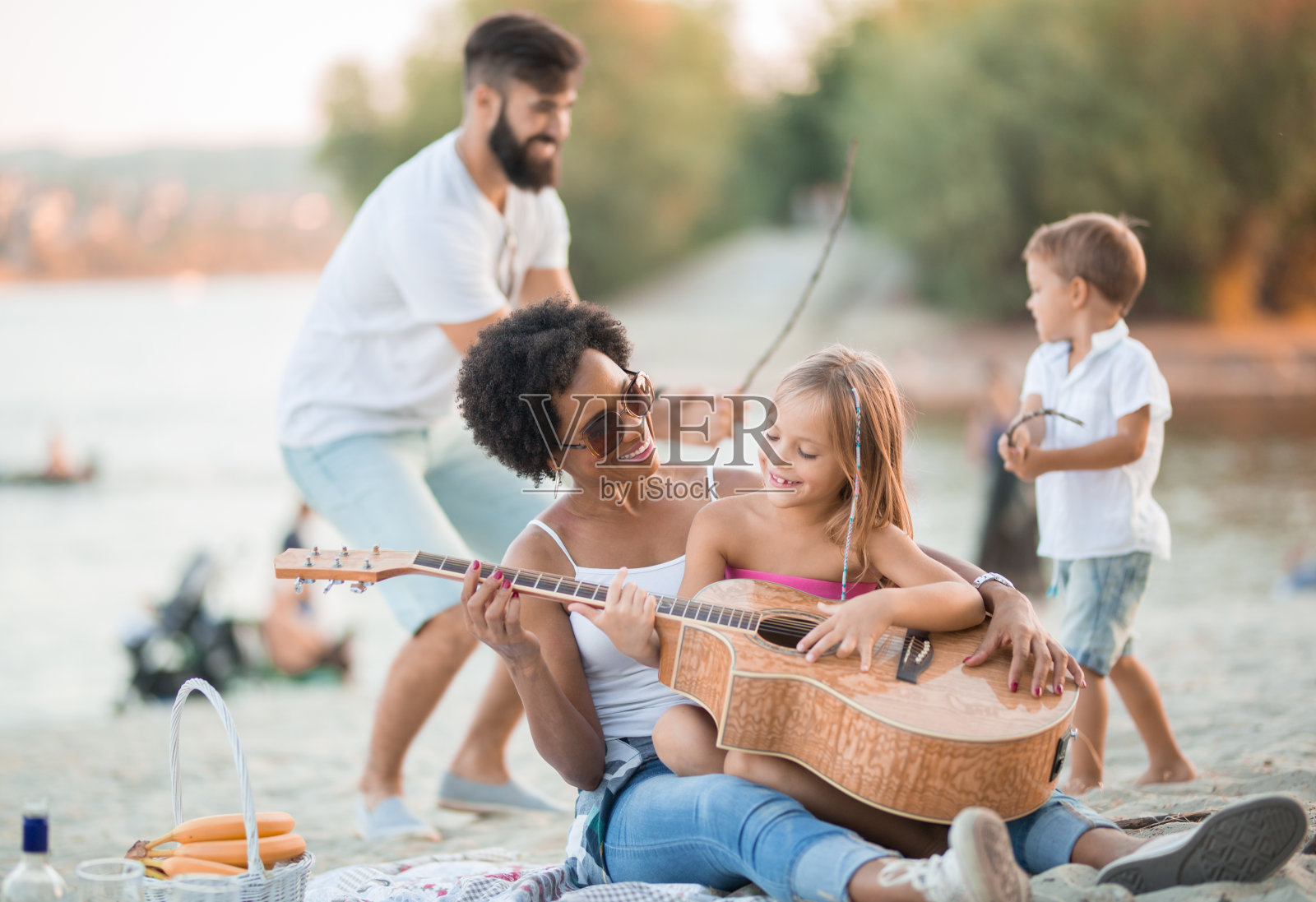 妈妈和女儿玩吉他，爸爸和儿子玩击剑照片摄影图片