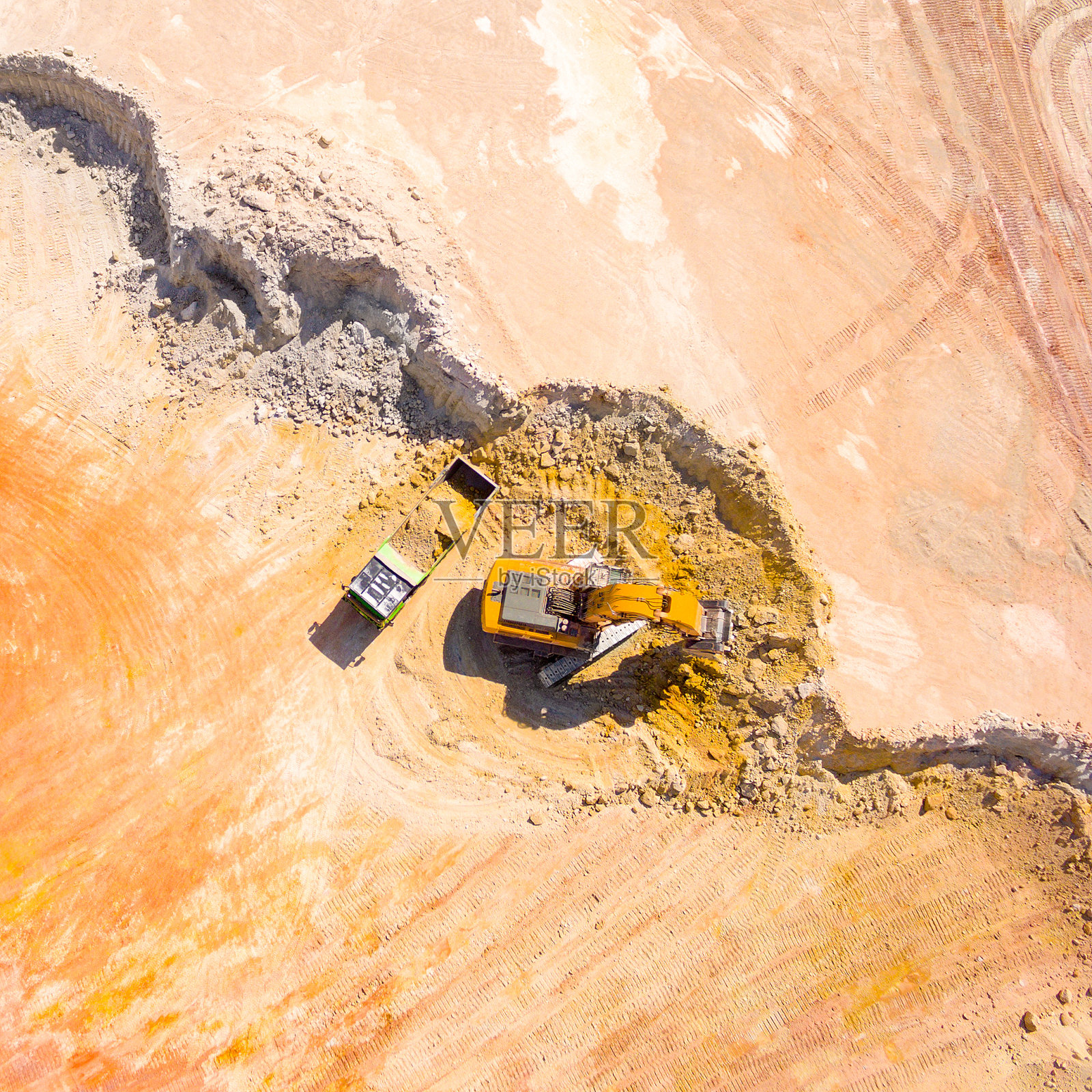 露天矿山挖掘机装载卡车的鸟瞰图。照片摄影图片