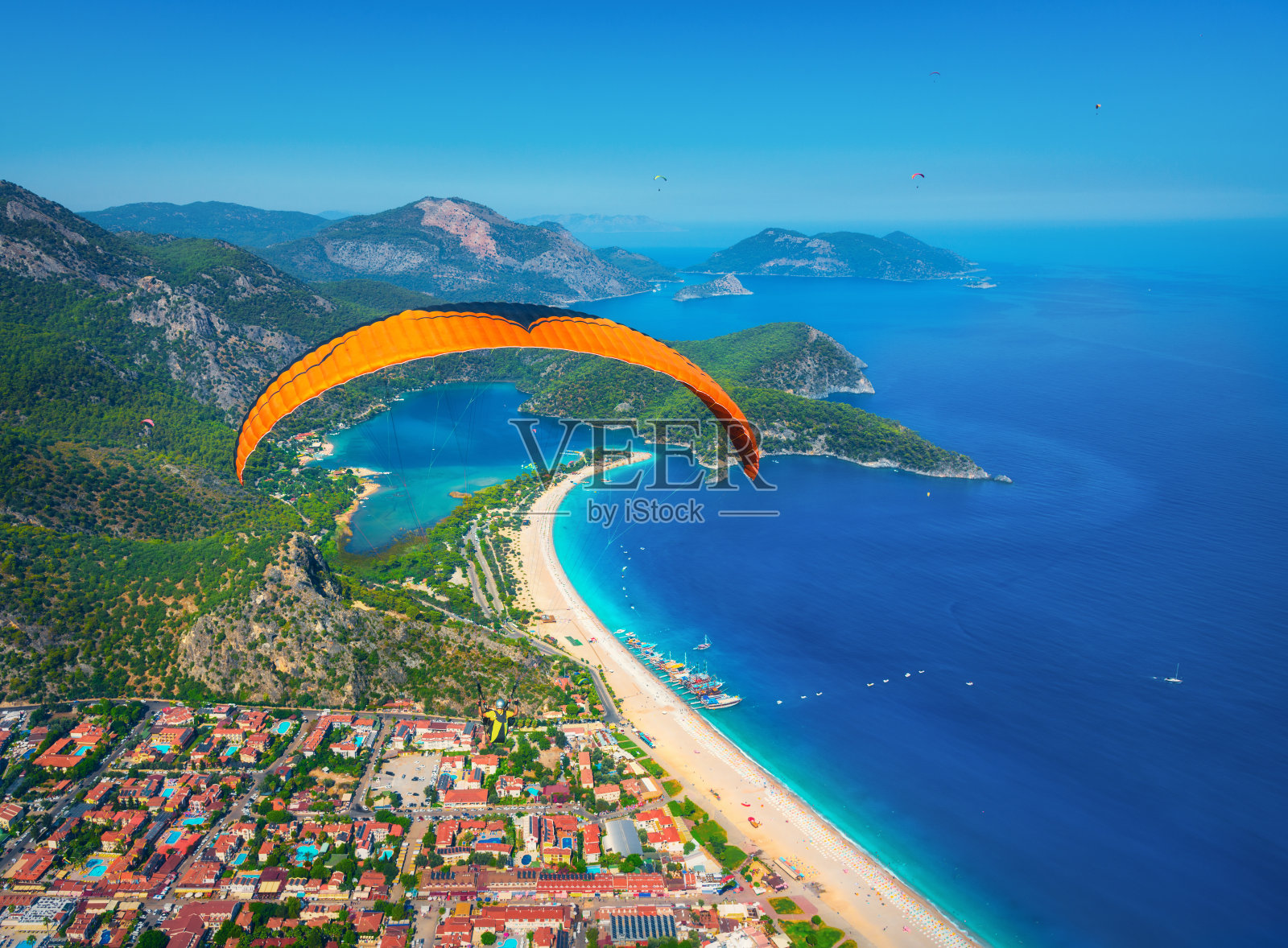 在空中滑翔。在阳光明媚的日子里，双人滑翔伞飞跃大海和碧水群山。鸟瞰图的滑翔伞和蓝色礁湖在Oludeniz，土耳其。极限运动。景观照片摄影图片