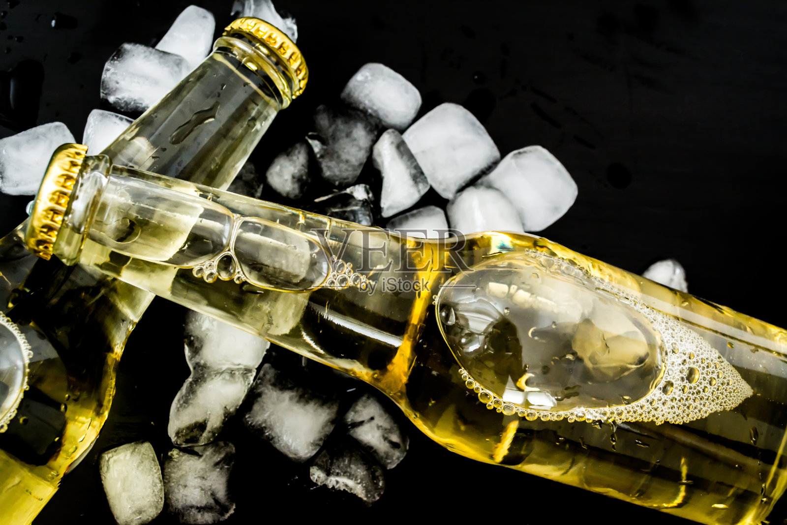 啤酒在瓶子与气泡在冰块近距离在一个黑暗的背景照片摄影图片