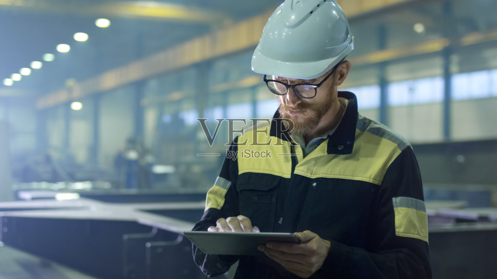 安全帽工程师正在一家重工业工厂里使用平板电脑。照片摄影图片