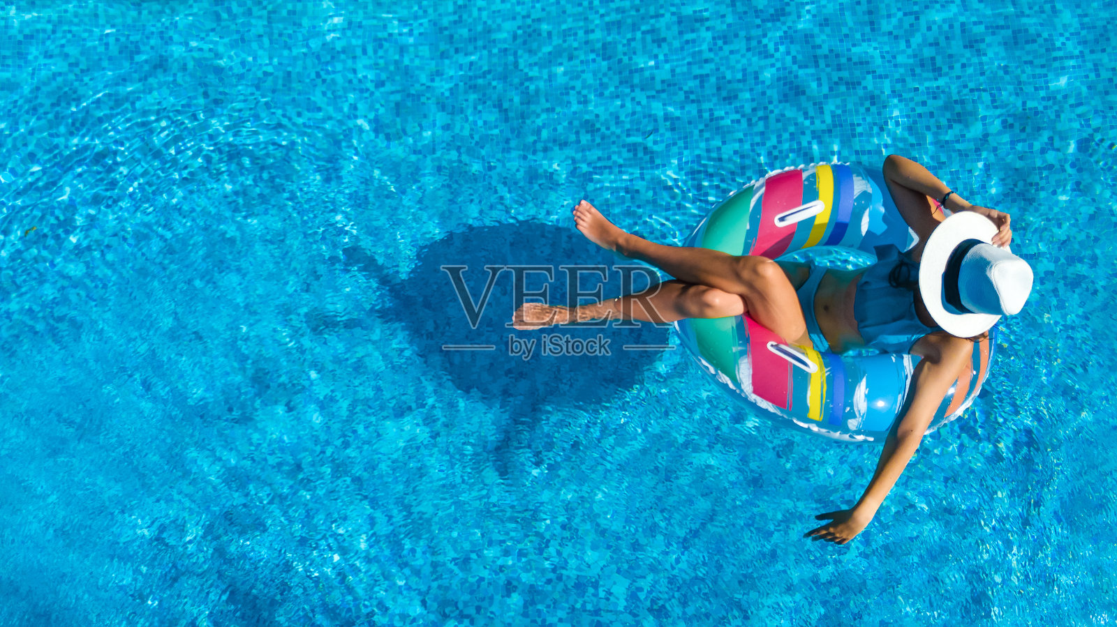 鸟瞰图美丽的女孩在游泳池从上面，游泳在充气圈甜甜圈和有乐趣的水在家庭度假照片摄影图片