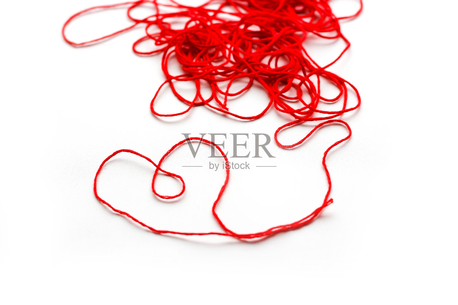 红色的毛线团。线画出了一颗心的形状。特写镜头。在白色背景上隔离照片摄影图片