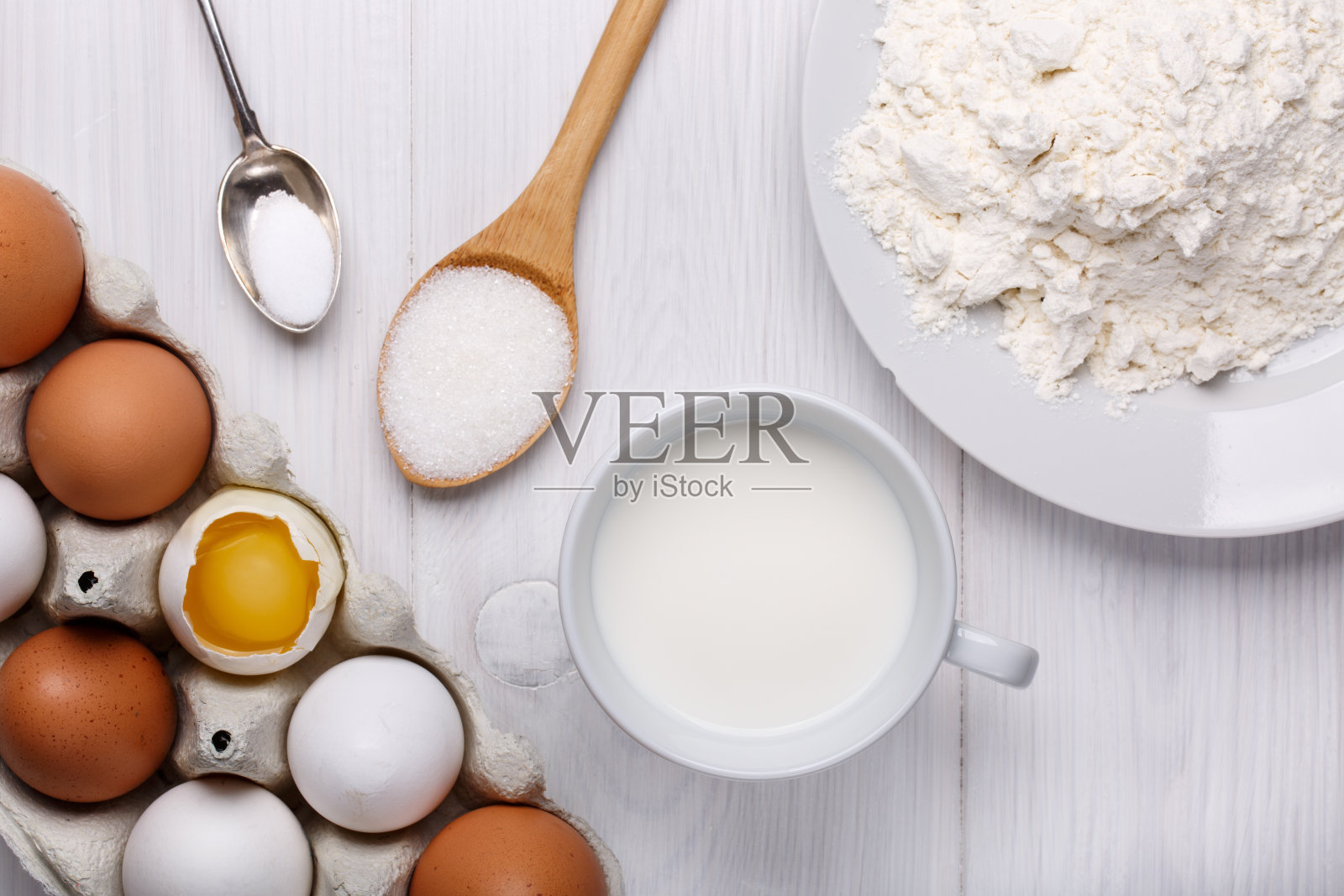 制作薄煎饼的原料(鸡蛋、面粉、牛奶、糖、盐)放在白色木桌上。前视图。照片摄影图片