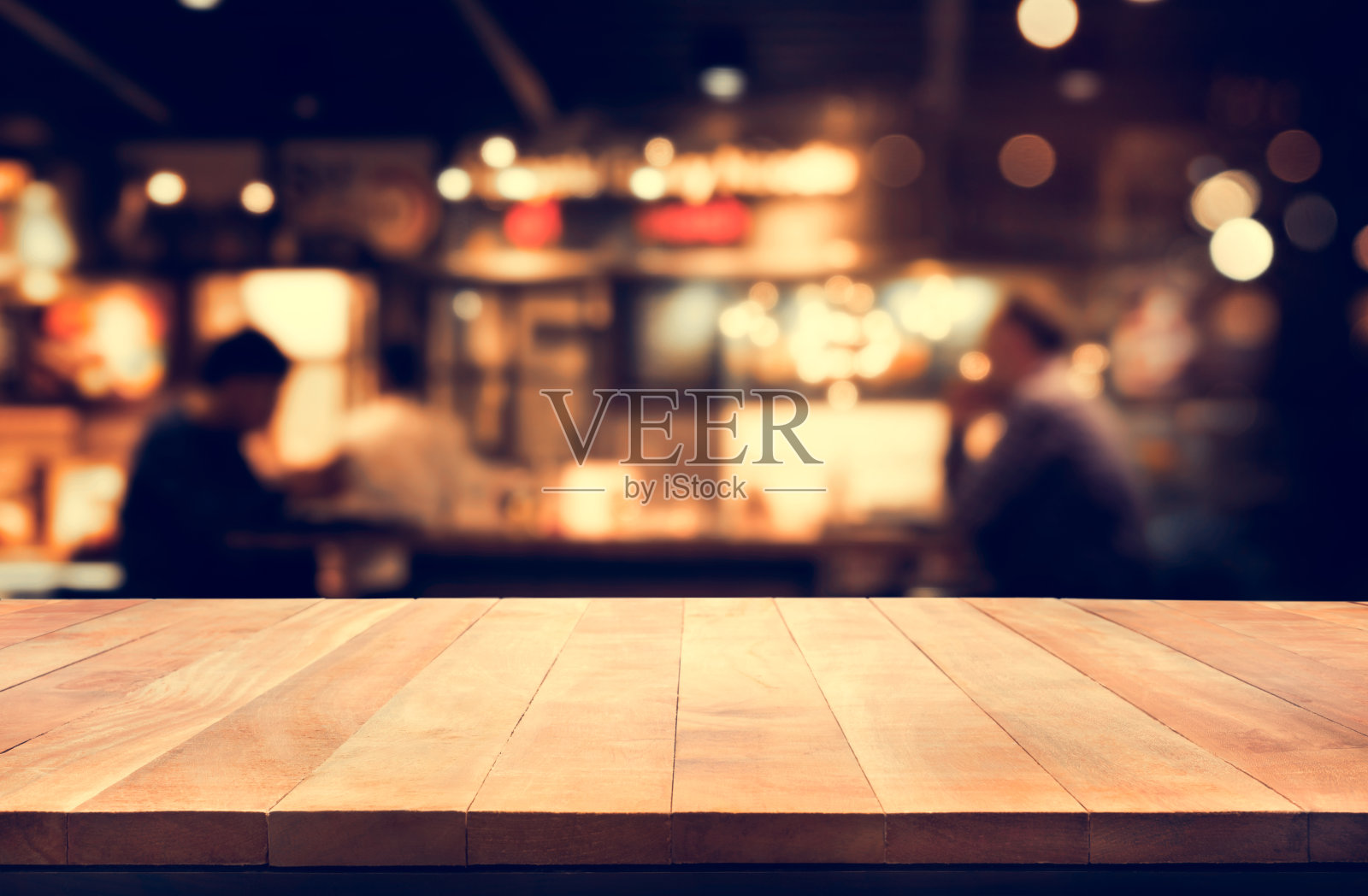 木质桌面与模糊的夜晚咖啡馆背景照片摄影图片