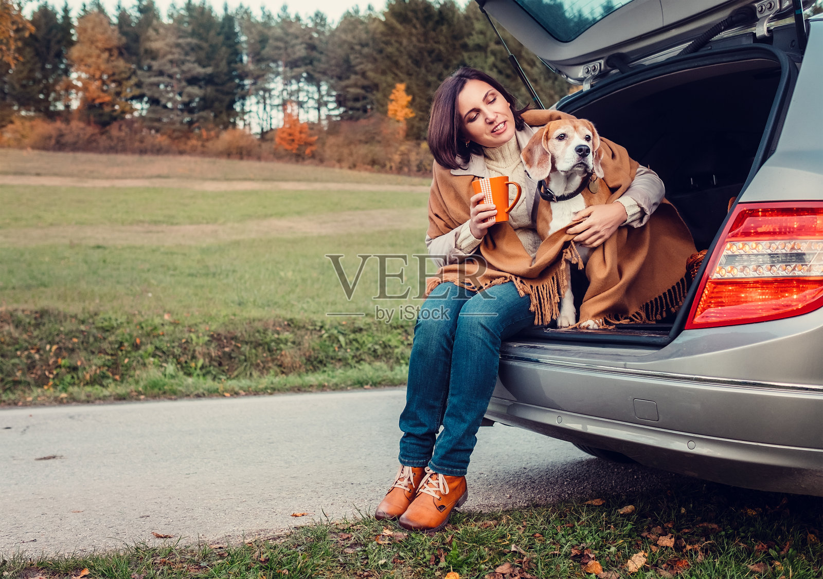 女人和狗一起坐在猫车里，喝着热茶照片摄影图片