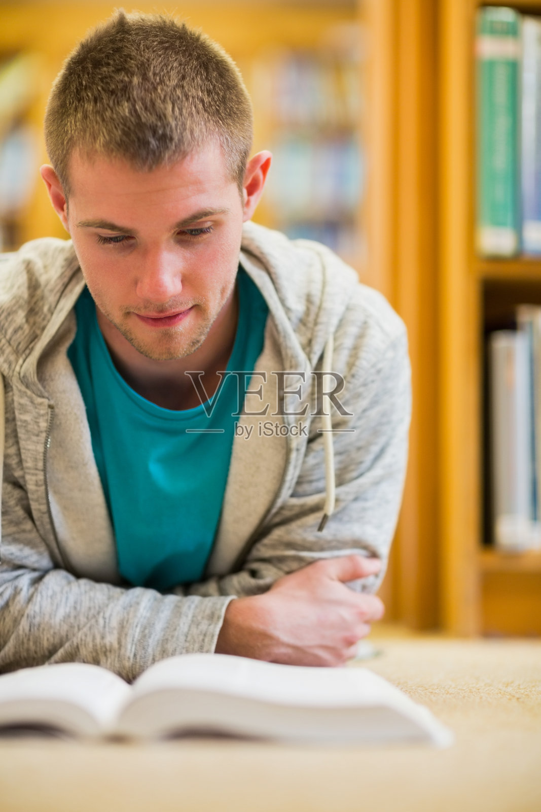 男学生在学院图书馆的地板上看书照片摄影图片