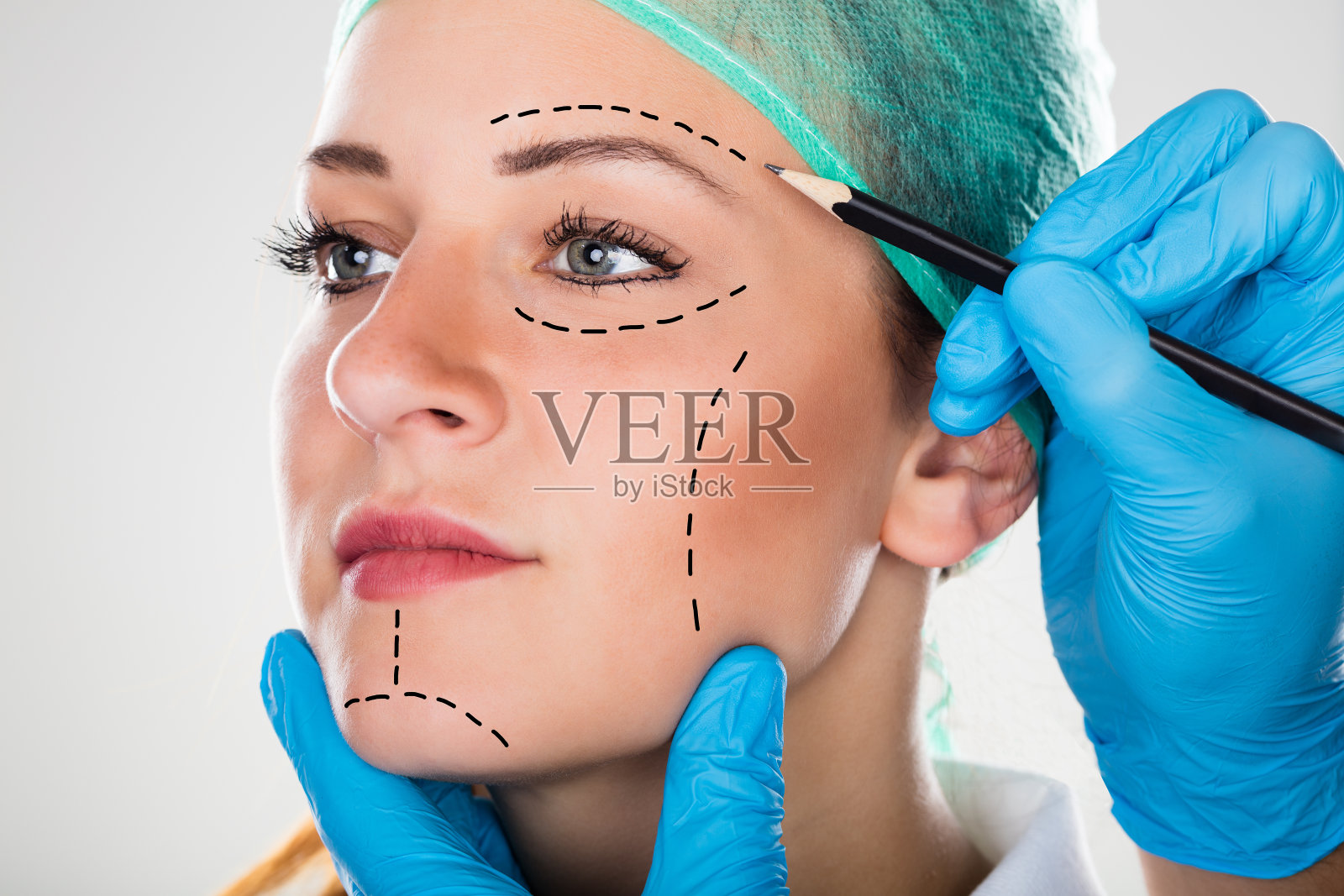 外科医生在妇女脸上画穿孔线照片摄影图片
