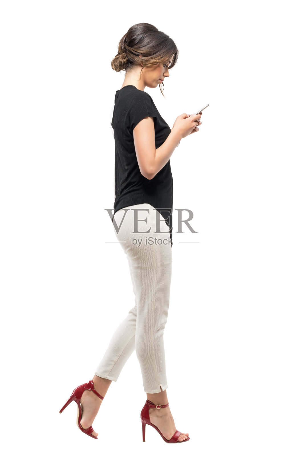 侧视图，忙碌的商务妇女在正装行走和打字的手机。照片摄影图片