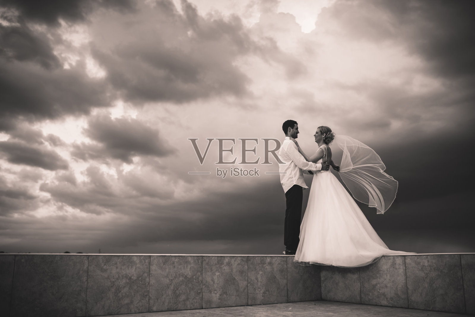 一对幸福的新婚夫妇站在阳台上。照片摄影图片