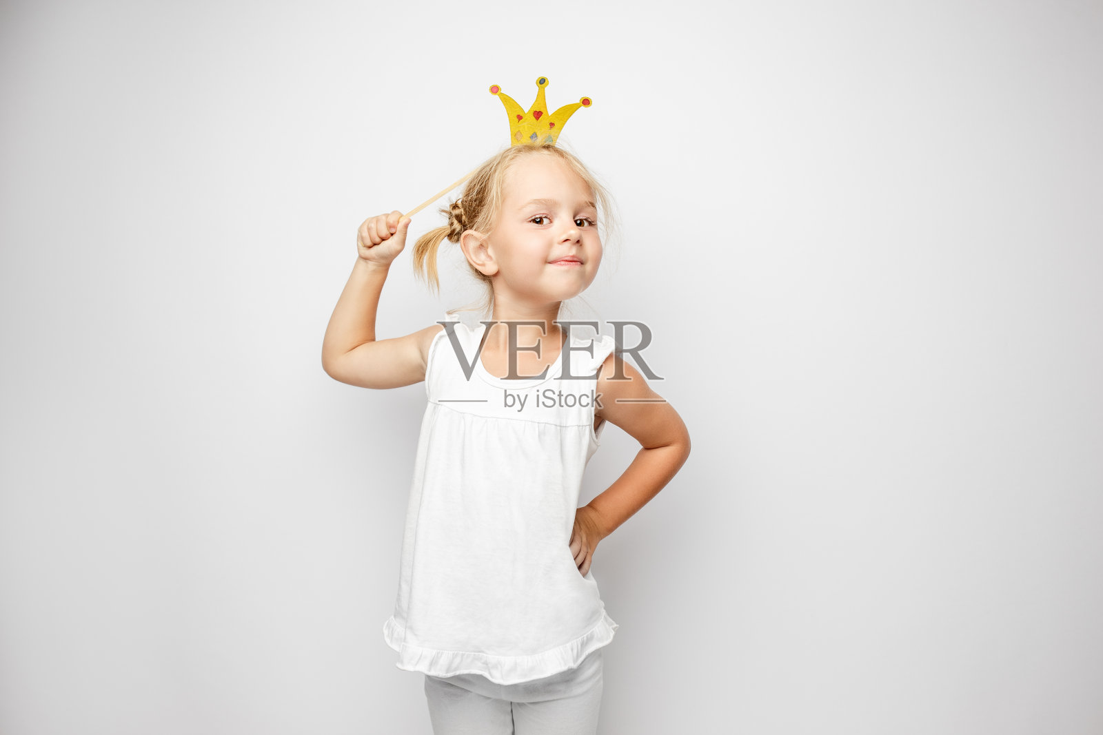美丽的小女孩与纸冠摆姿势在白色的背景照片摄影图片
