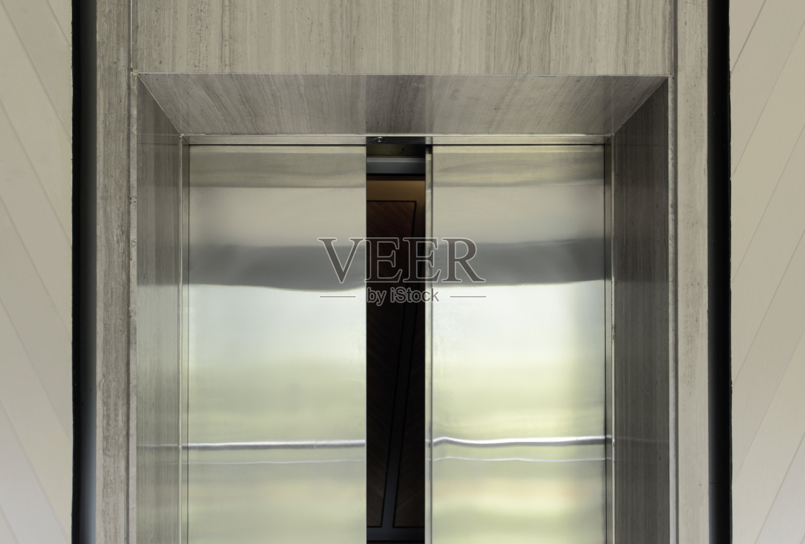 微微打开的电梯门。电梯门套由金属不锈钢制成，安装在商务办公楼门口、入口大厅或走廊的电梯上。照片摄影图片