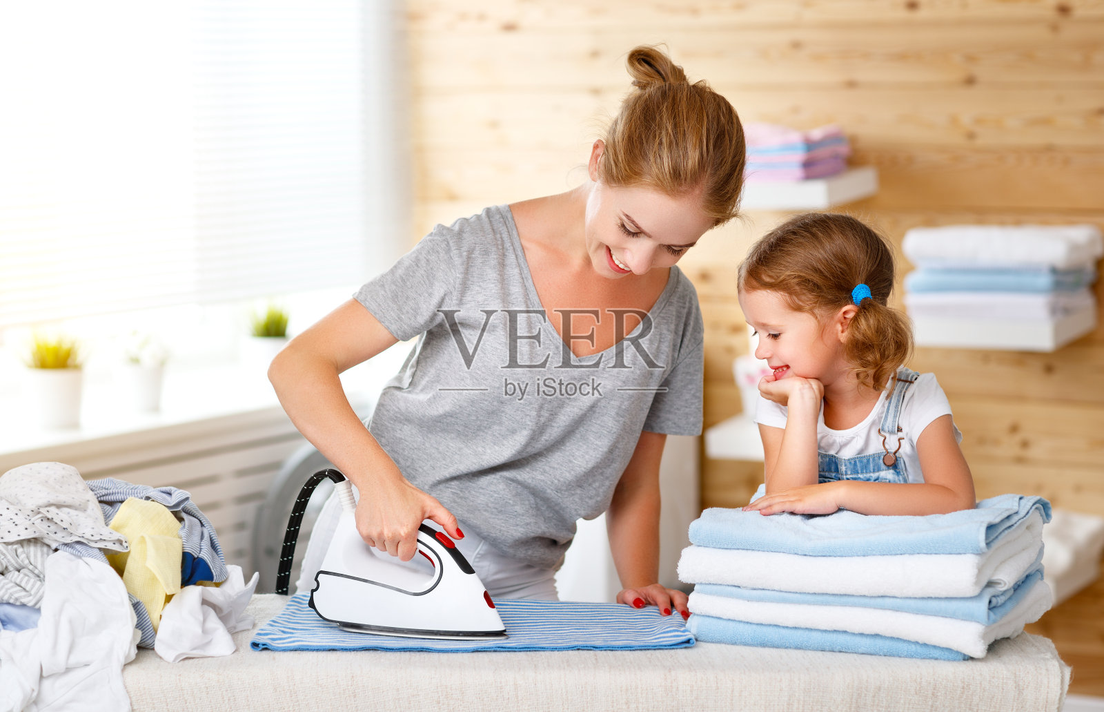 幸福的家庭，母亲，家庭主妇和孩子女儿在洗衣熨烫衣服照片摄影图片