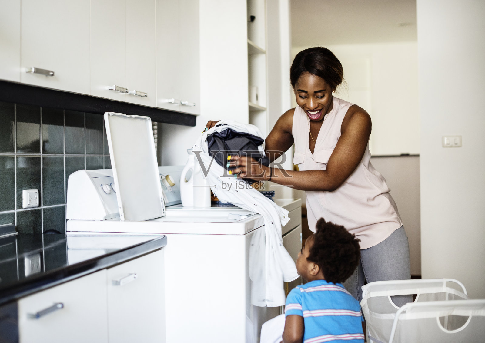 非洲裔小孩帮妈妈洗衣服照片摄影图片