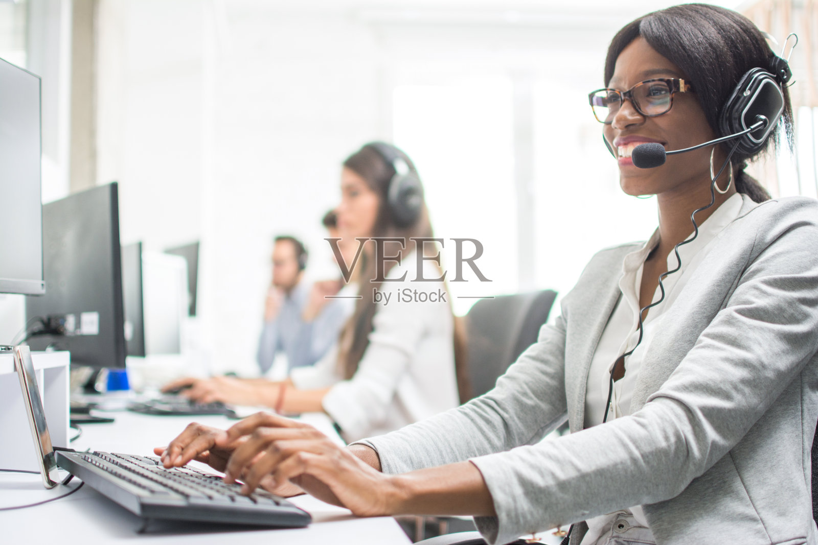友好的女性热线接线员，戴着耳机在办公室。代理客服代表:业务和办公理念。照片摄影图片