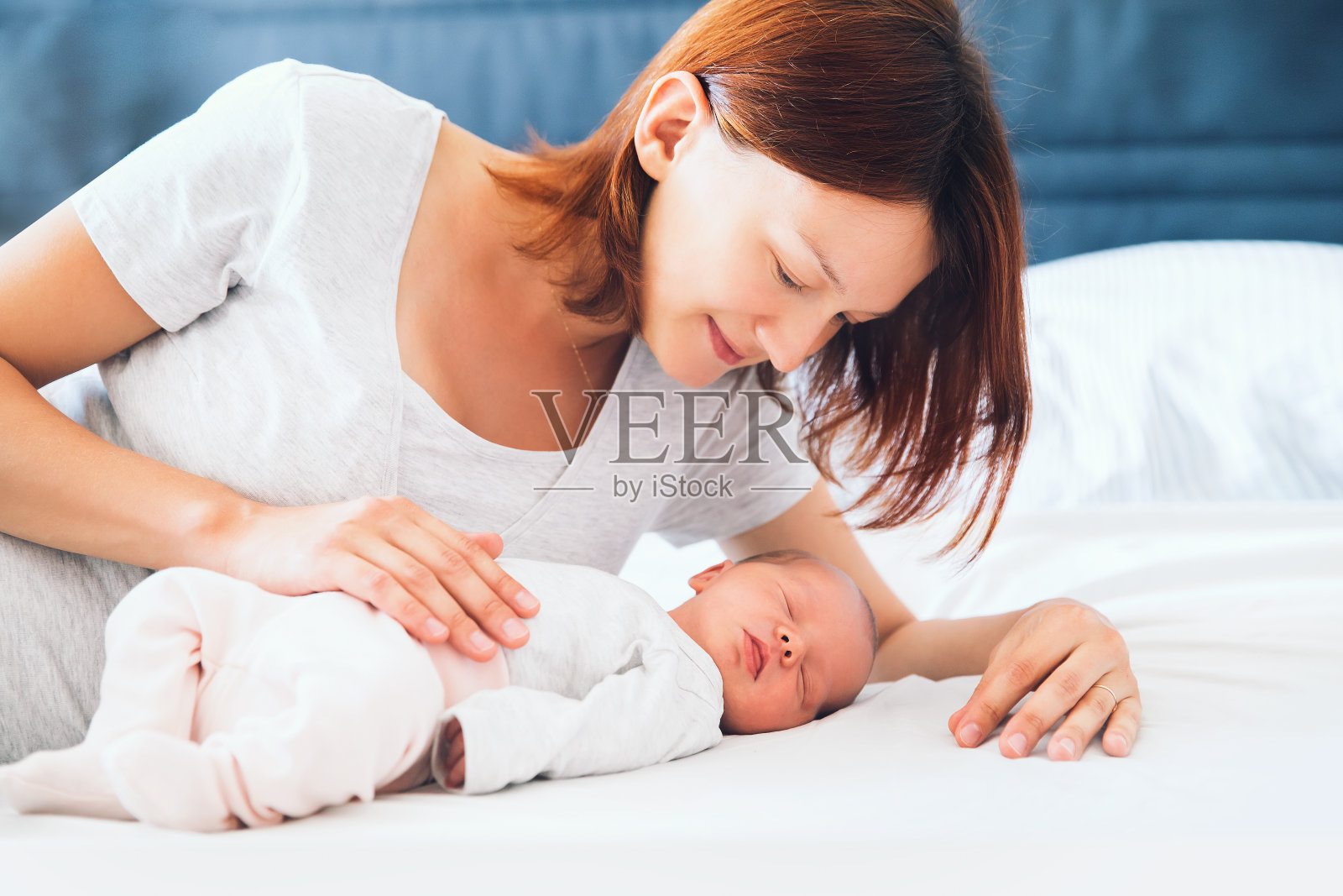 年轻的母亲看着她刚出生的婴儿。照片摄影图片