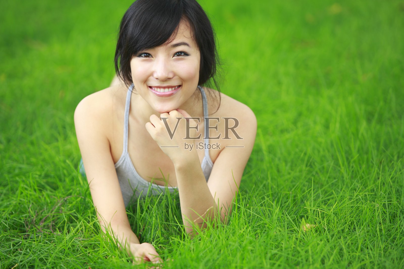 一个年轻漂亮的亚洲女人躺在新鲜的草地上照片摄影图片