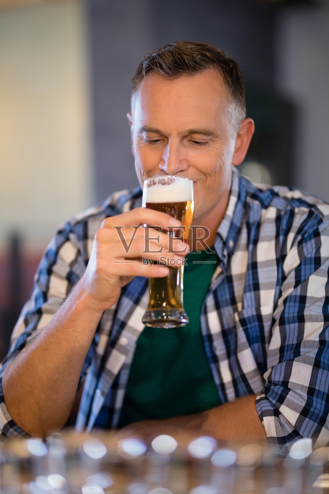 微笑的男人在柜台喝着啤酒照片摄影图片
