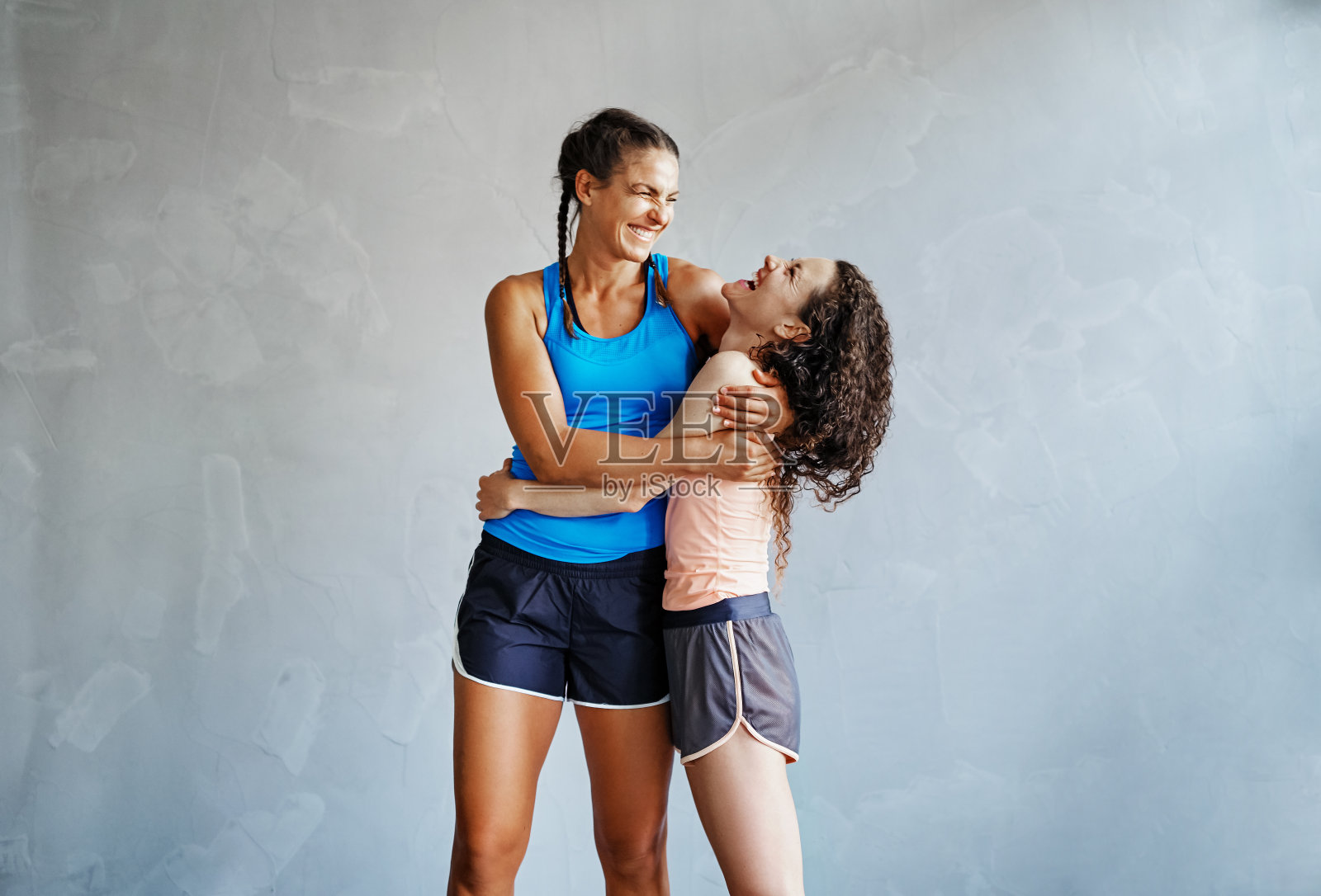 两个笑着的女朋友在锻炼后拥抱在一起照片摄影图片