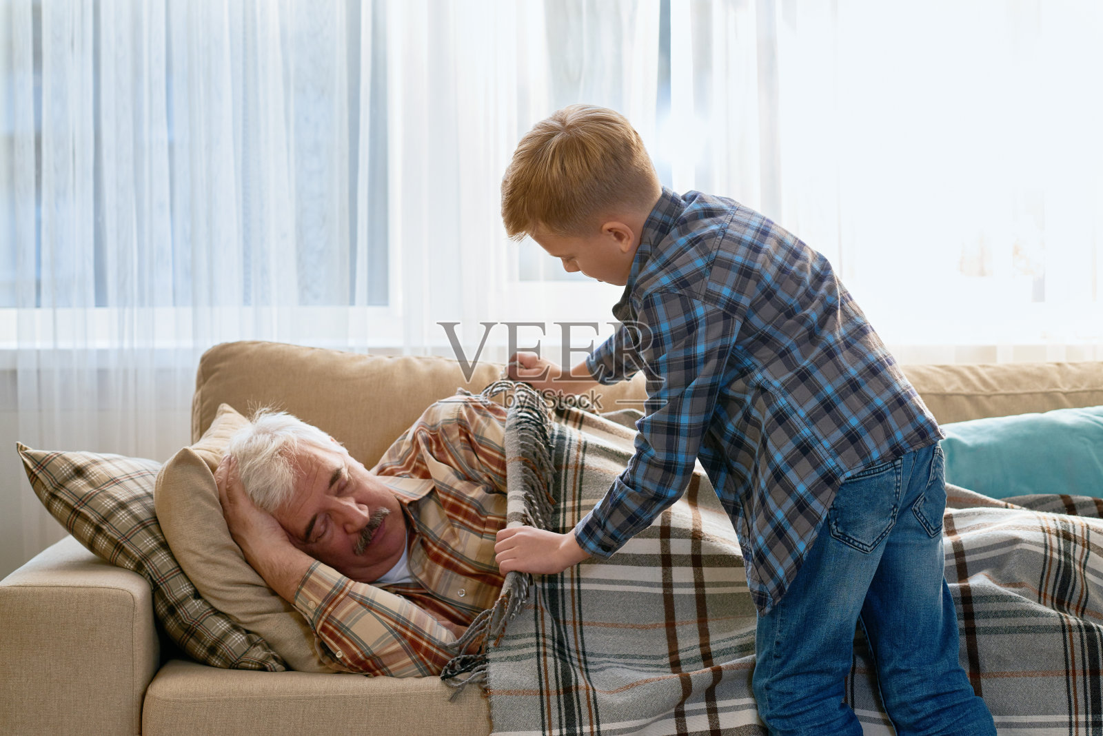 小心翼翼的孙子给爷爷盖上毯子照片摄影图片